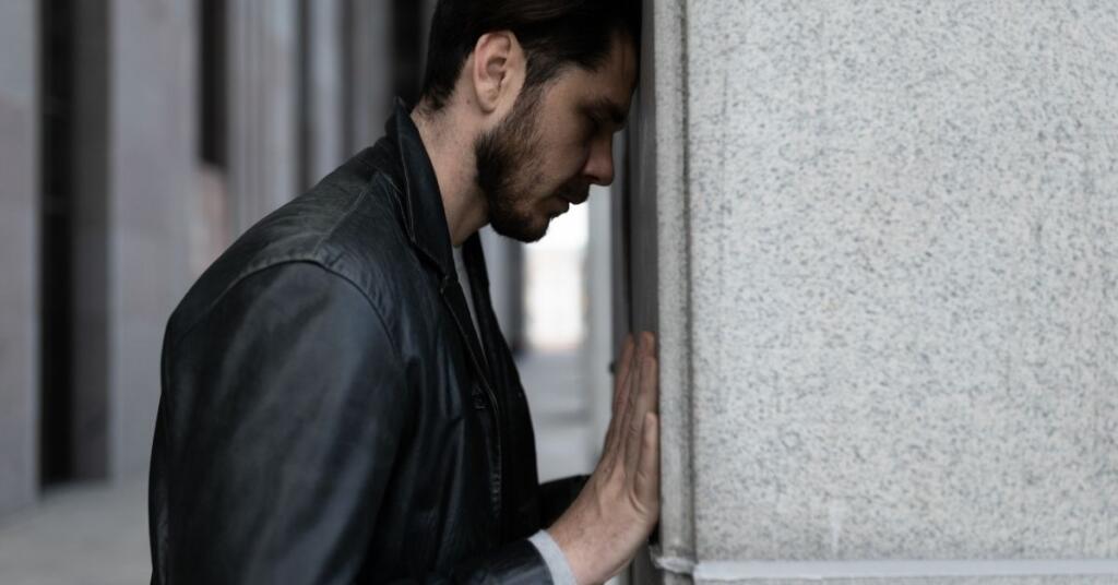 A man in Stress. Standing behind the wall