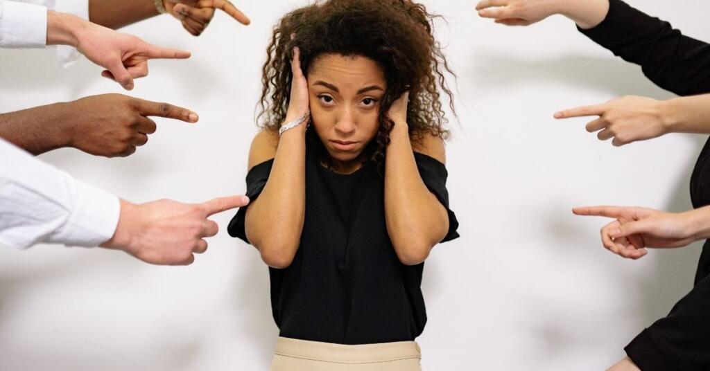 A woman standing behind the wall and many peoples finger on near her face